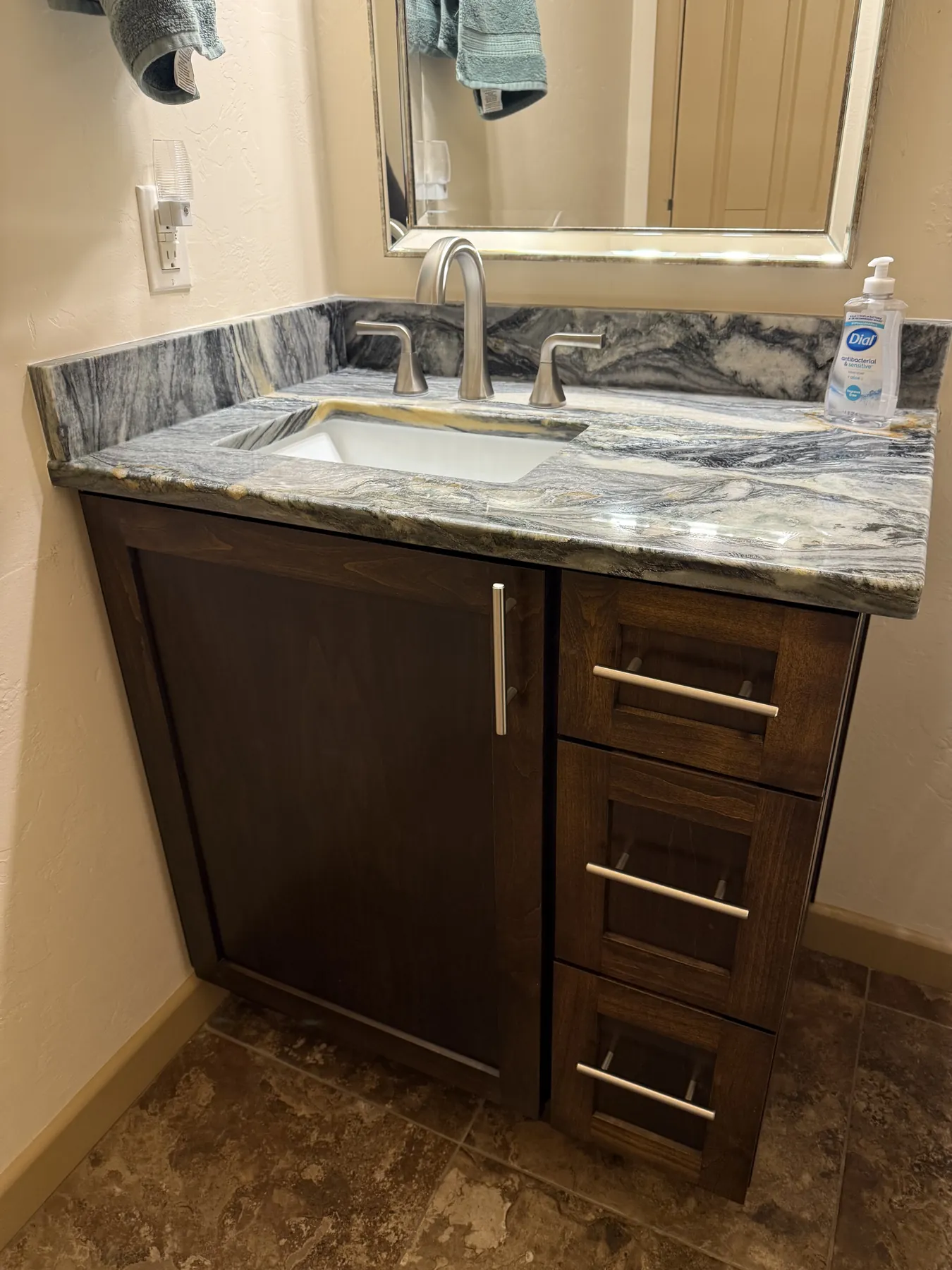 Dark bathroom vanity with expressive stone countertop and sink