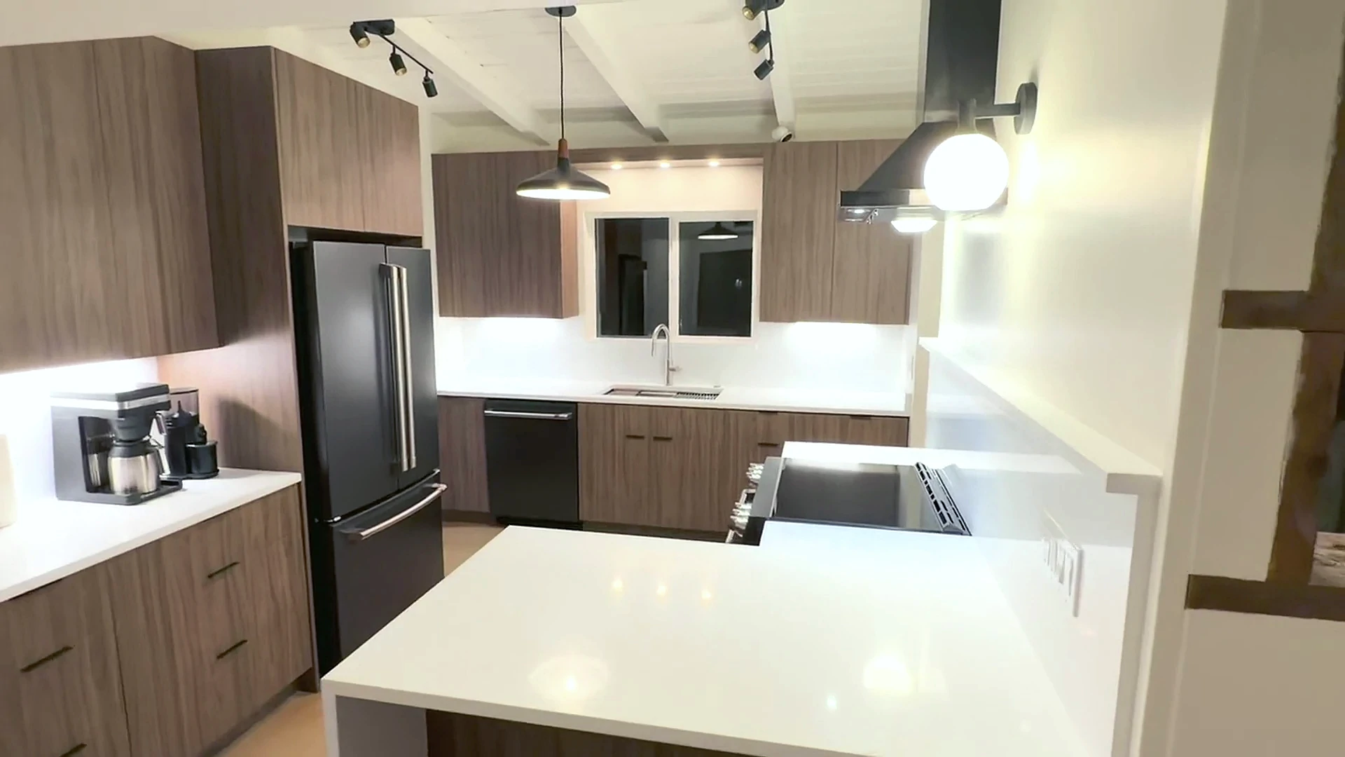 Completed walnut cabinetry kitchen with white countertops and island