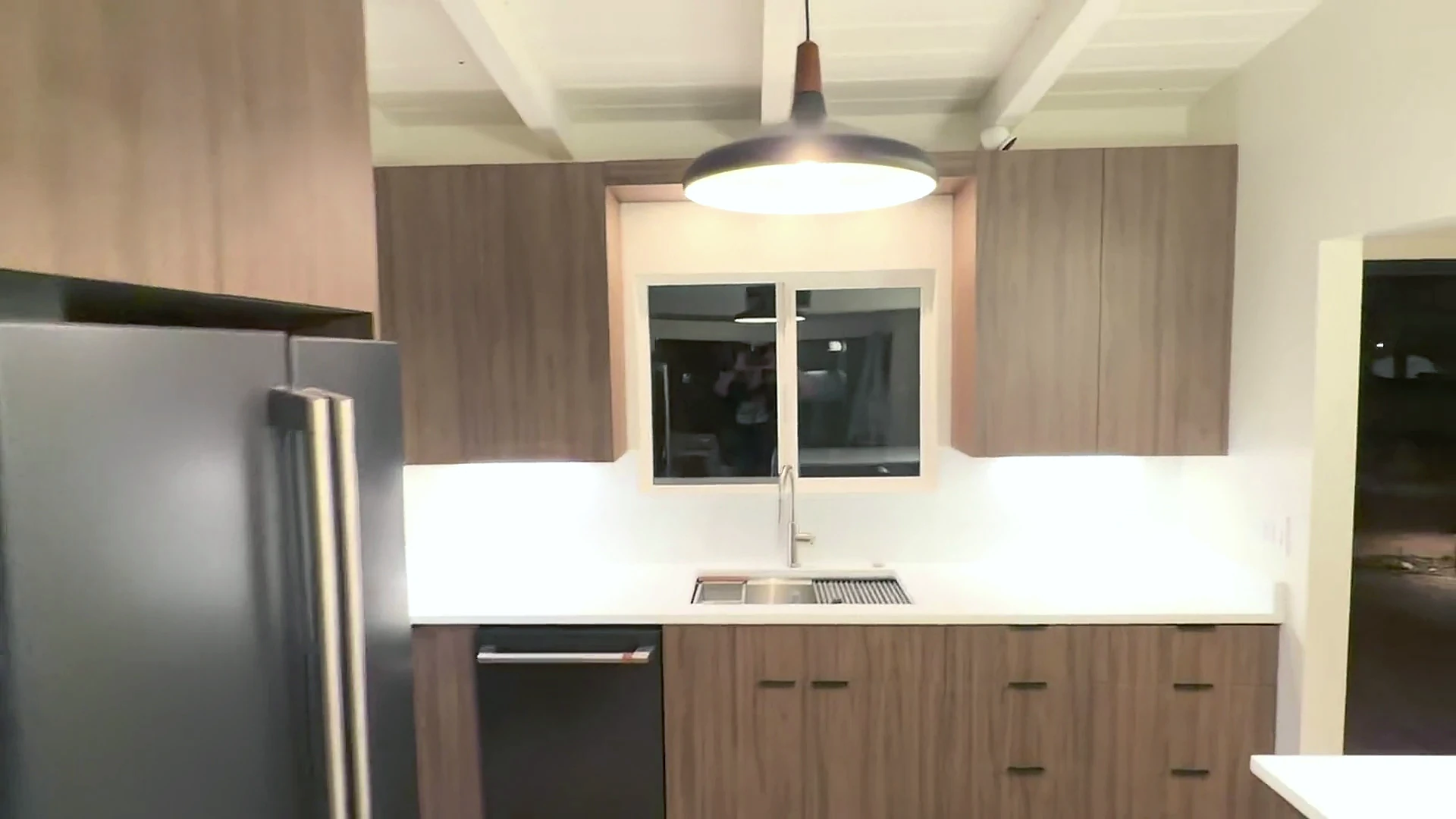 Centered view of the cabinetry, sink, counters and pendant lighting