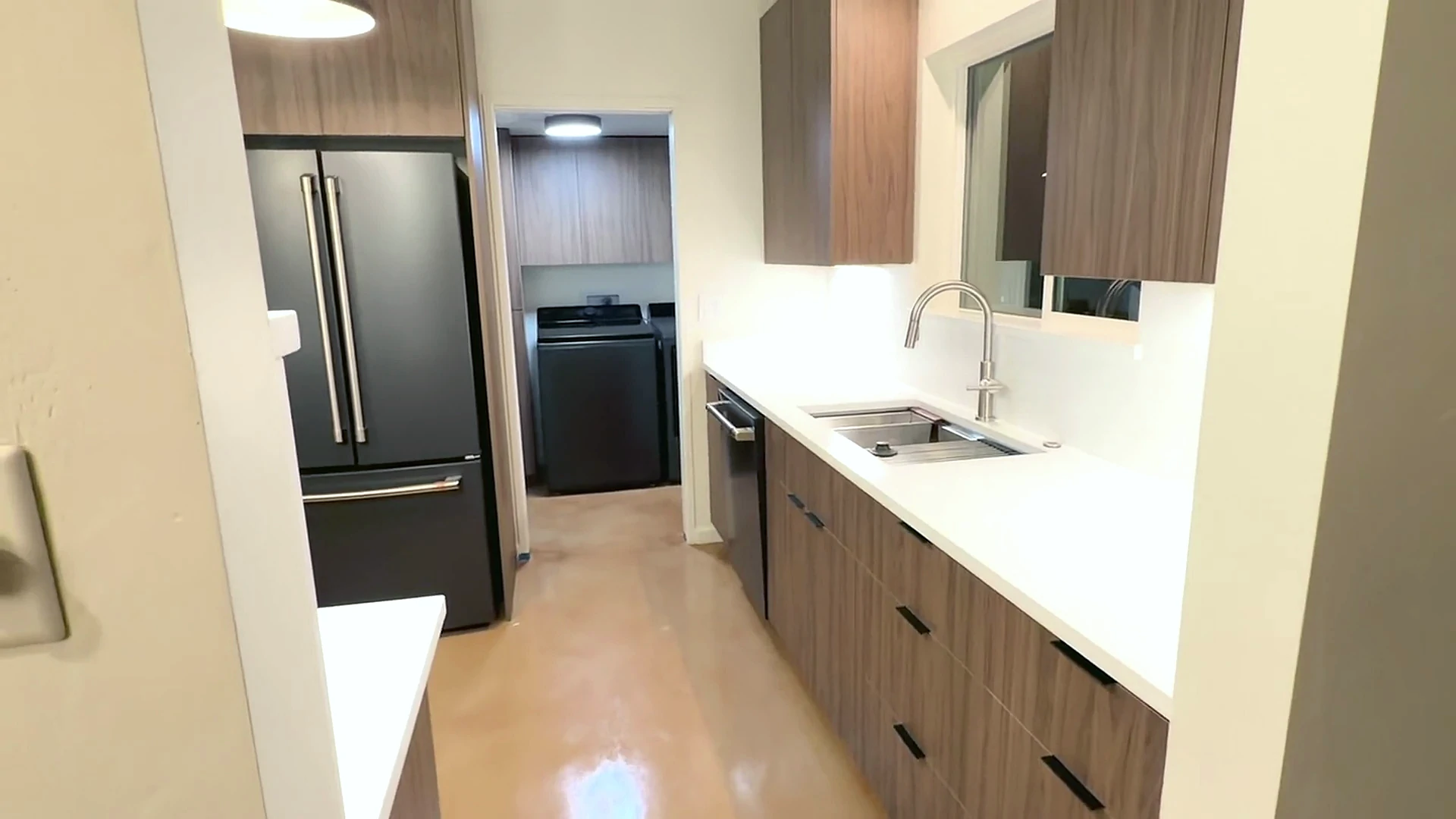 Refrigerator and long countertop view through the completed kitchen