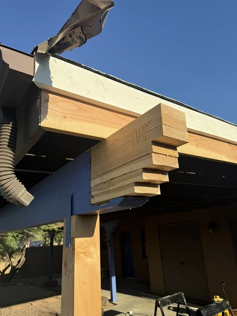 New dimensional-lumber work at an existing covered patio roof edge during structural carpentry