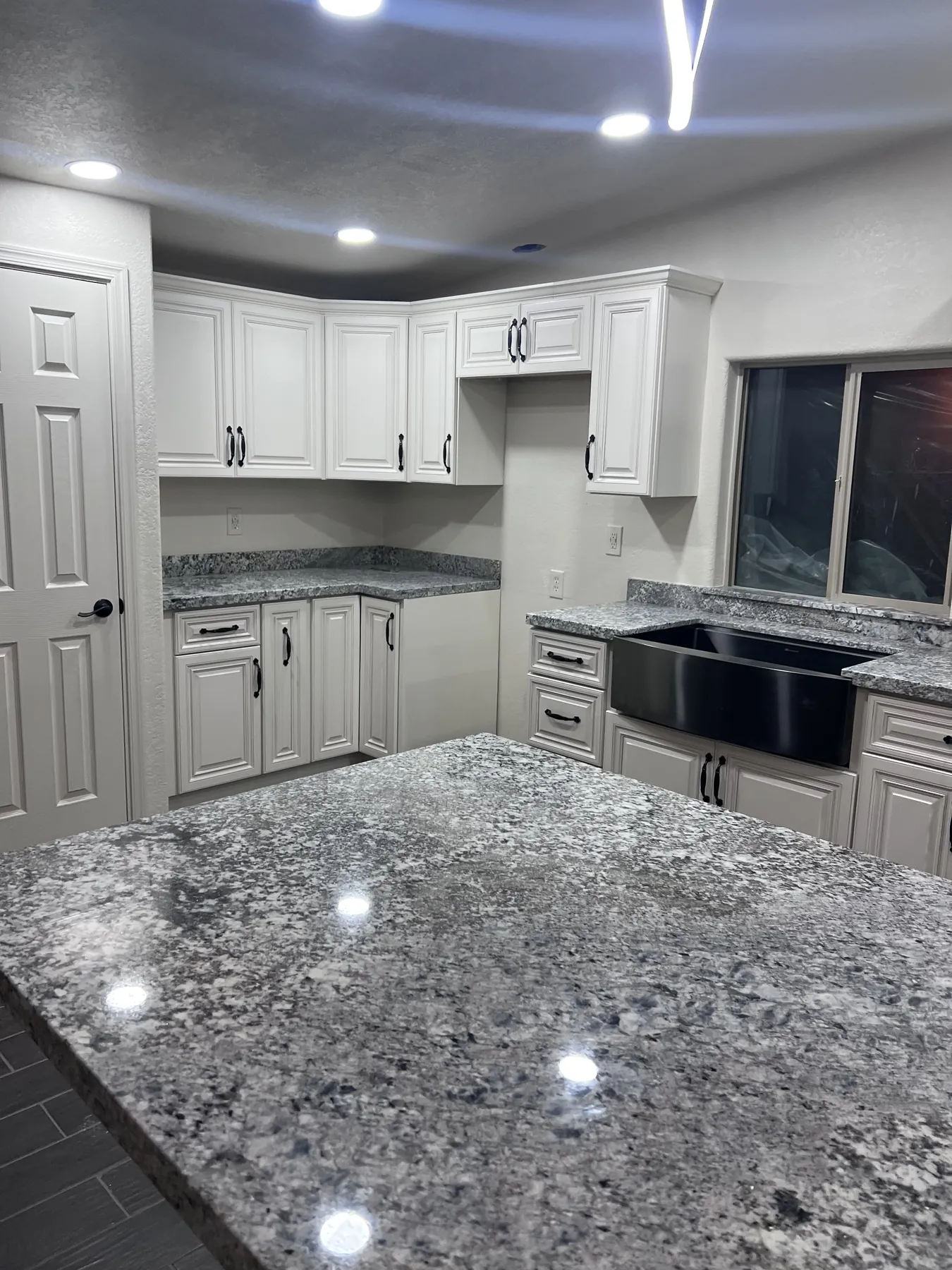 Finished white kitchen cabinetry with stone island countertop