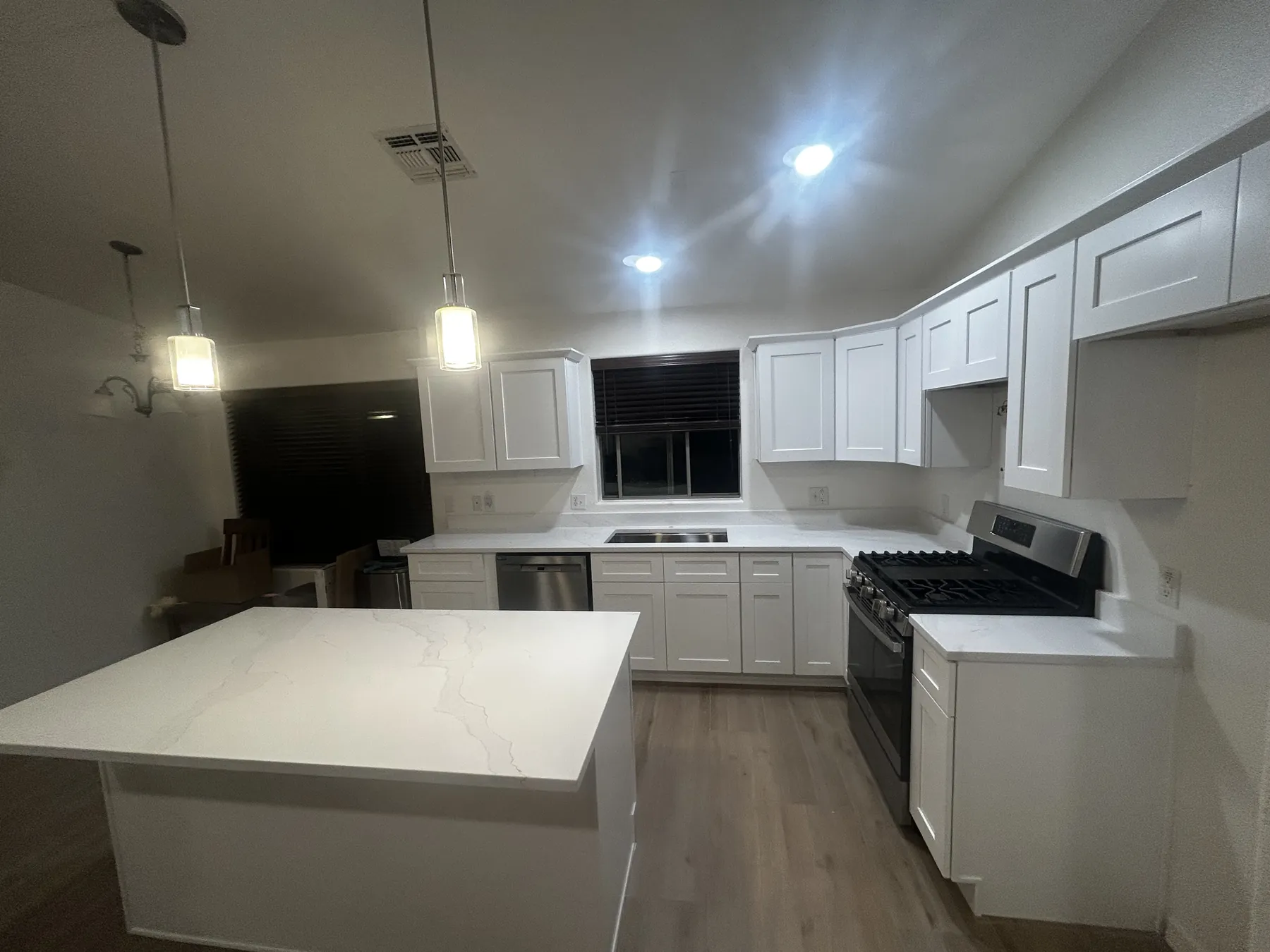 Completed white kitchen remodel with island and coordinated lighting