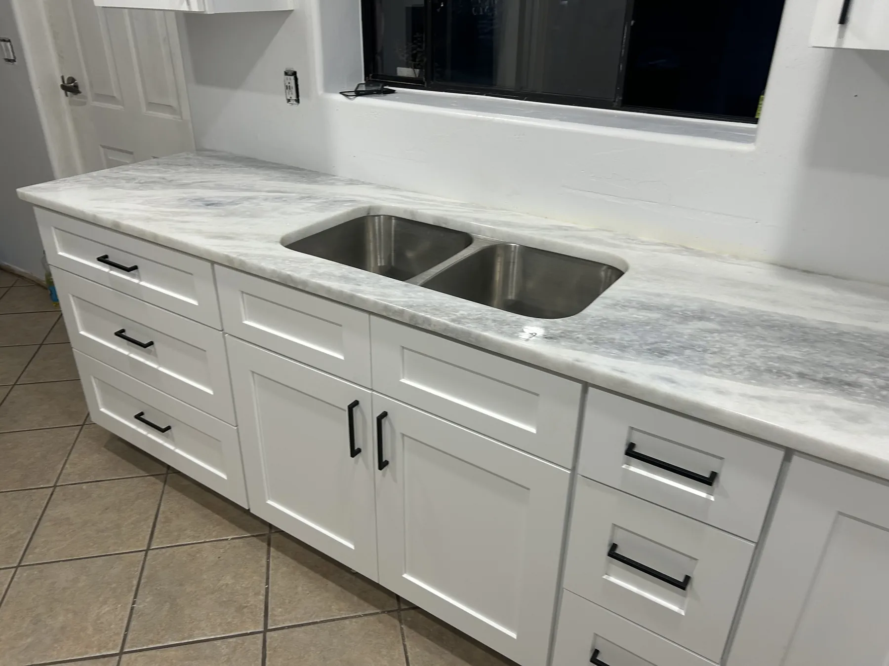 Completed kitchen sink, light countertop and white base cabinetry