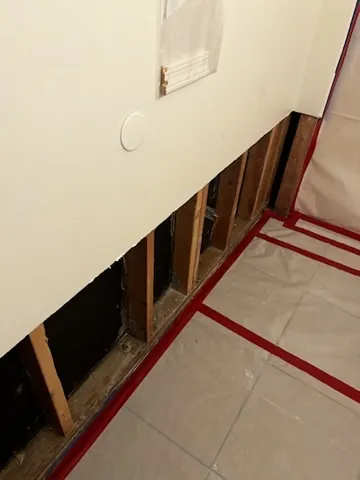 Lower wall opened with taped floor protection during mitigation work