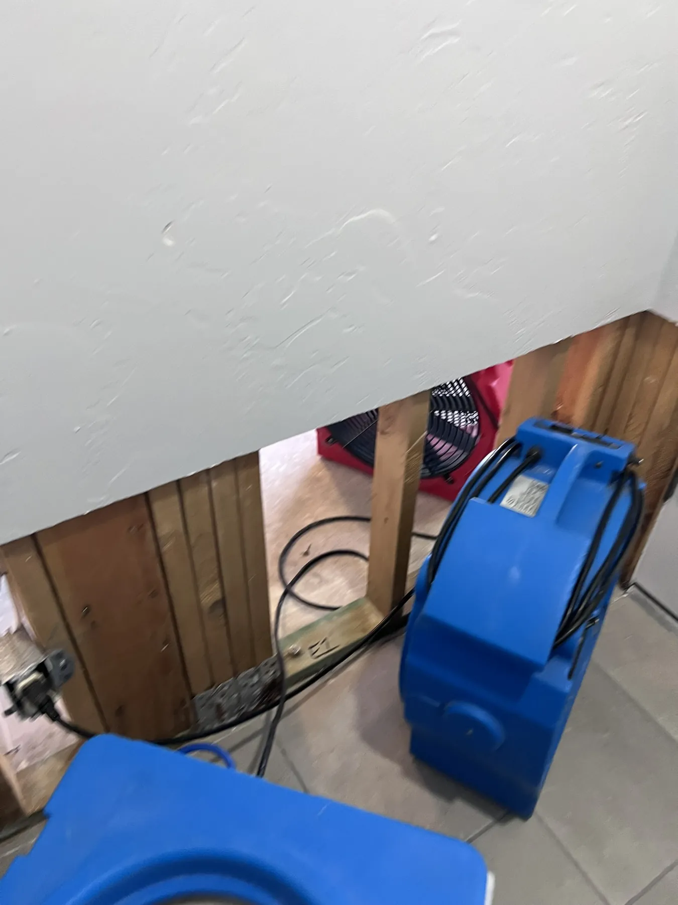 Air movers operating beside an opened lower wall cavity during structural drying